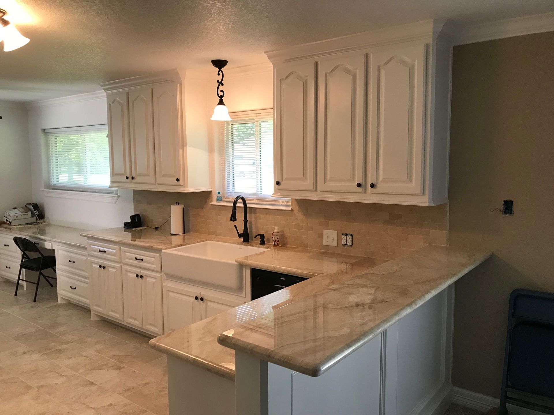 Bright kitchen with white cabinets, beige countertops, and a window over the sink