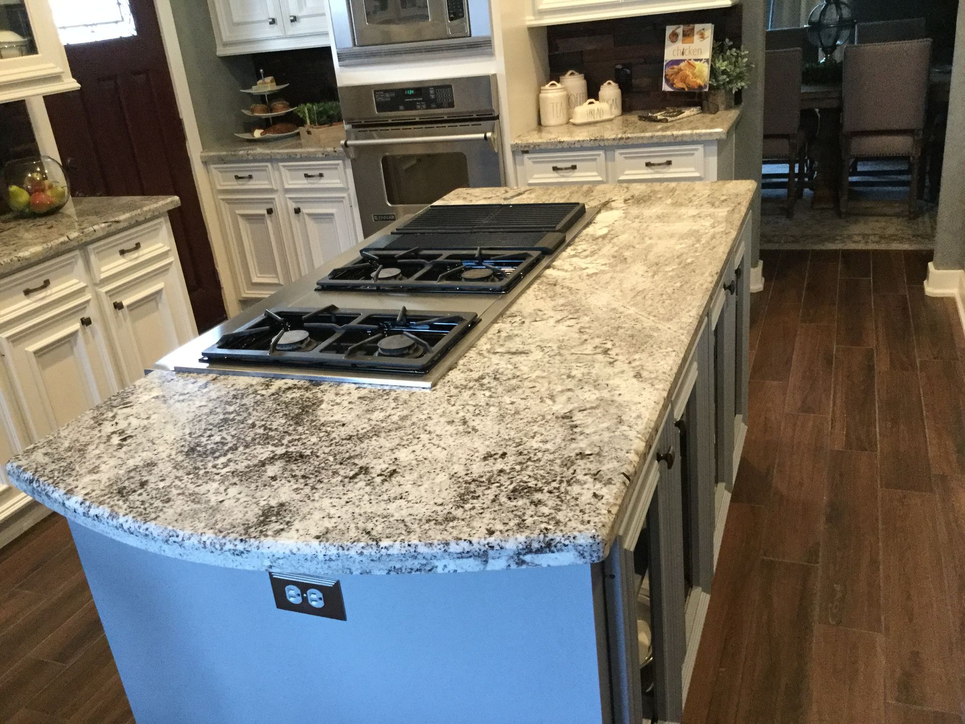 Kitchen island with granite countertop and built-in stovetop, in a bright modern kitchen.