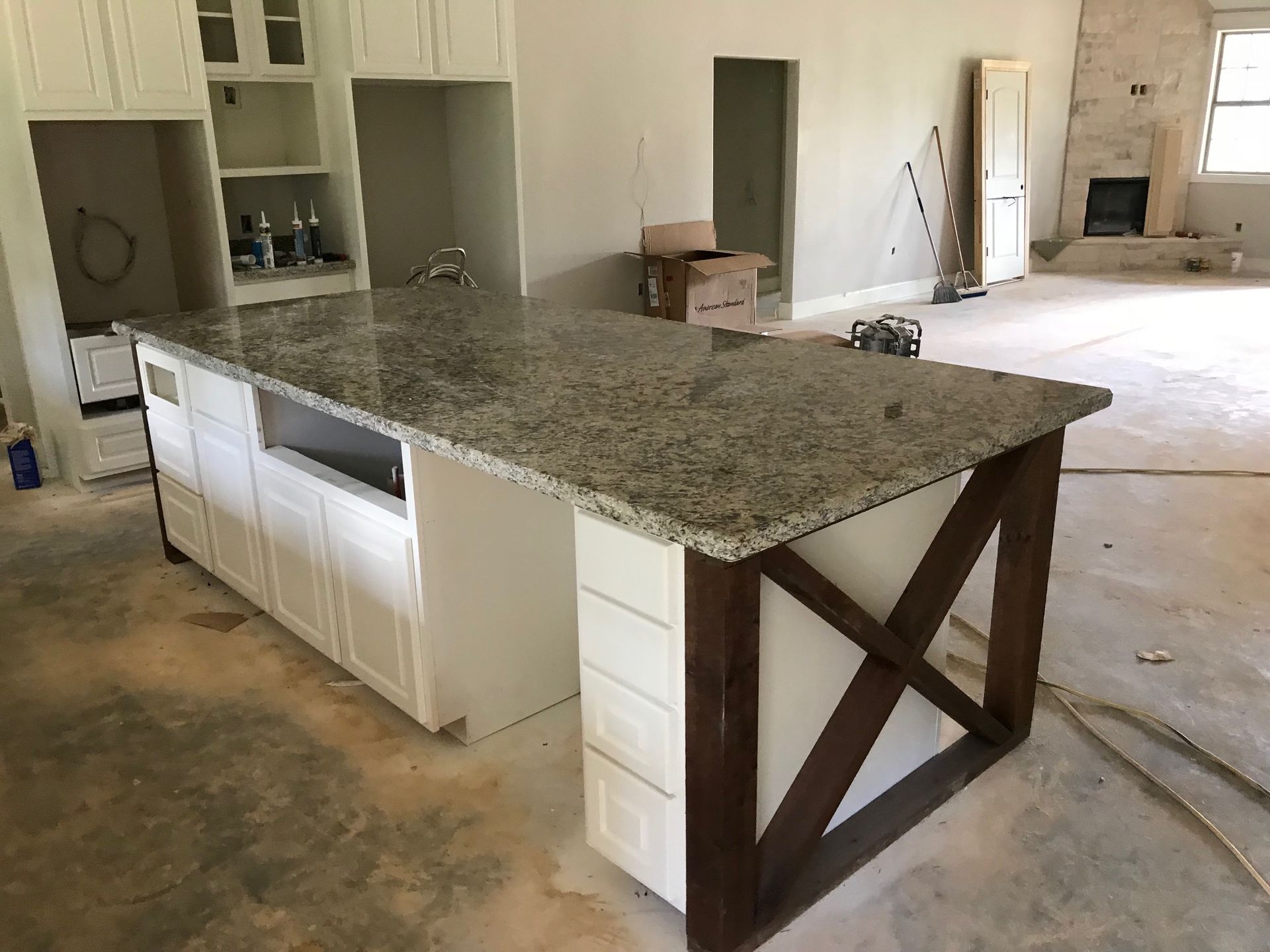Kitchen island with granite countertop and white cabinets in an unfinished room