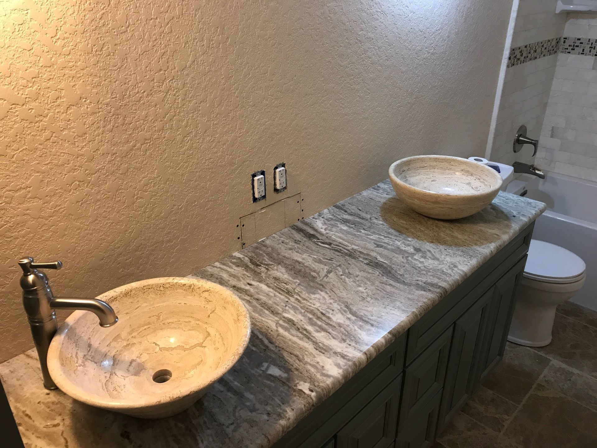 Bathroom vanity with two stone vessel sinks and a marble countertop
