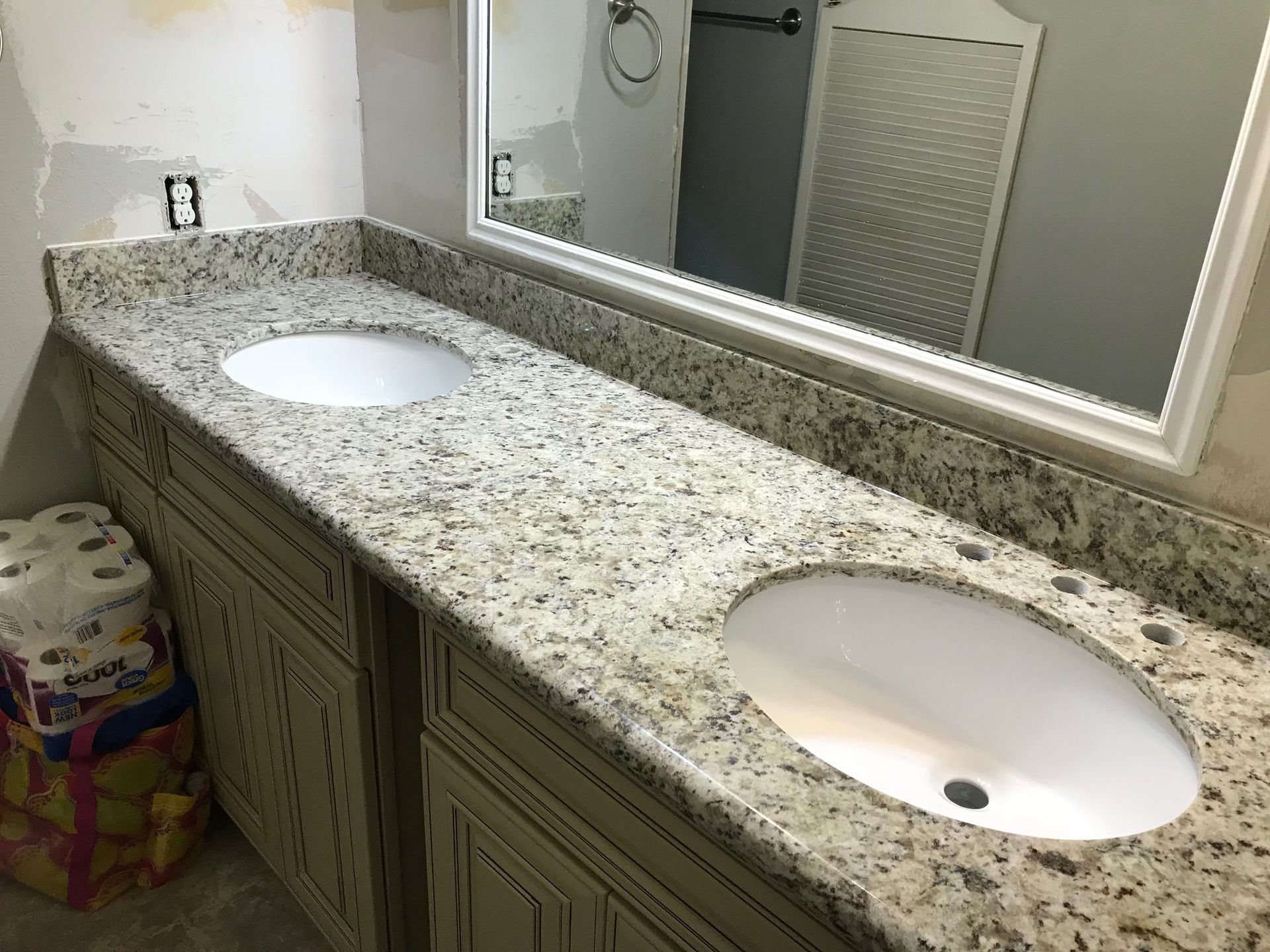 Bathroom vanity with double sinks, granite countertop, and large mirror