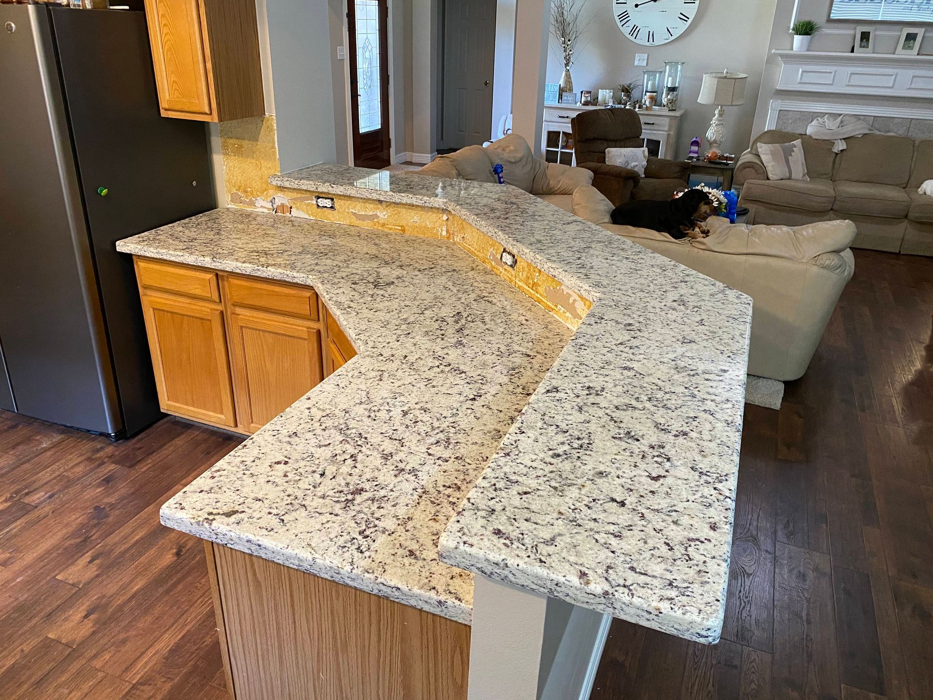 Granite kitchen island with curved countertop in a living room open to a sofa and dining area