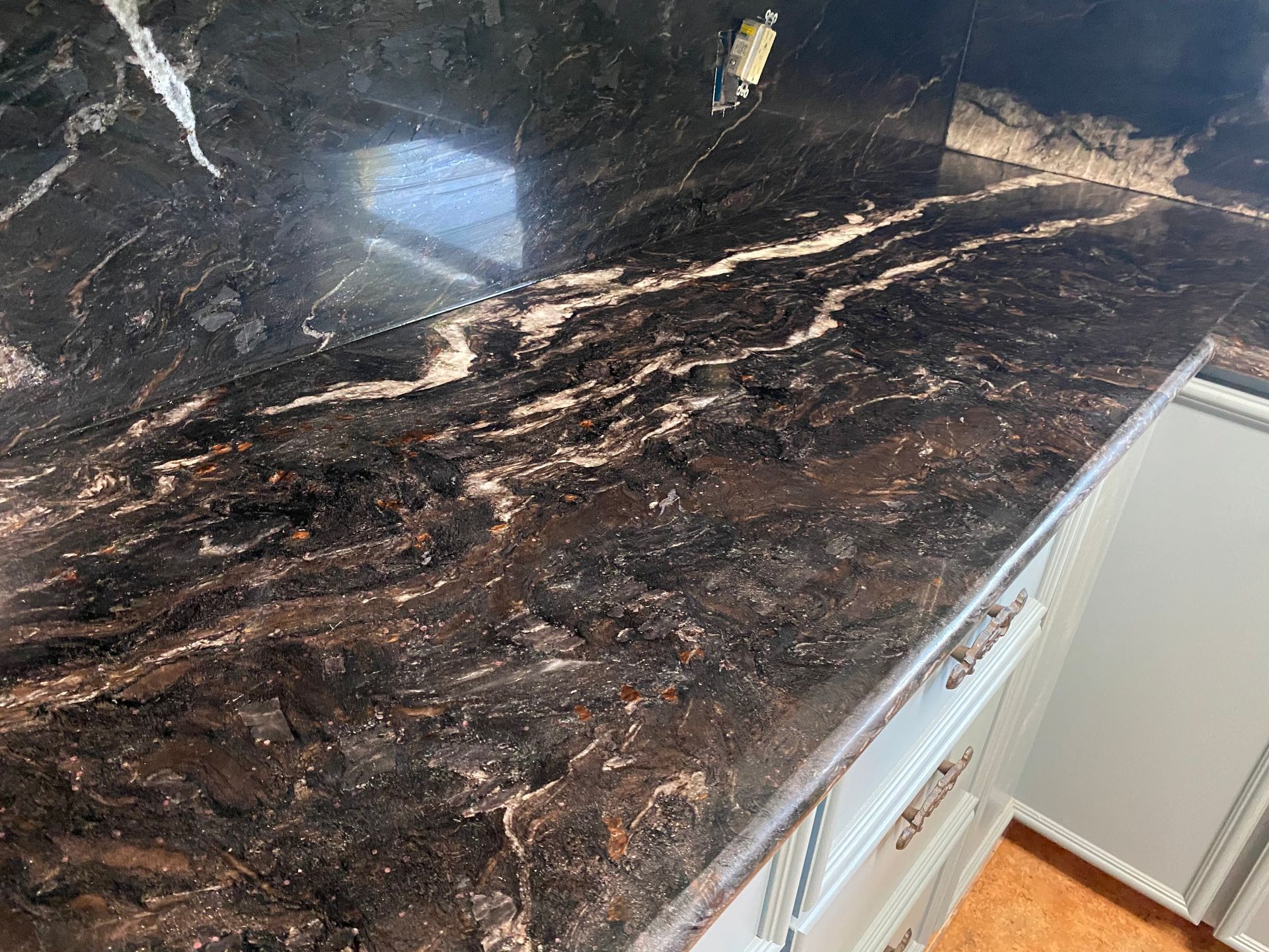 Dark polished granite countertop with white and brown veining in a kitchen.