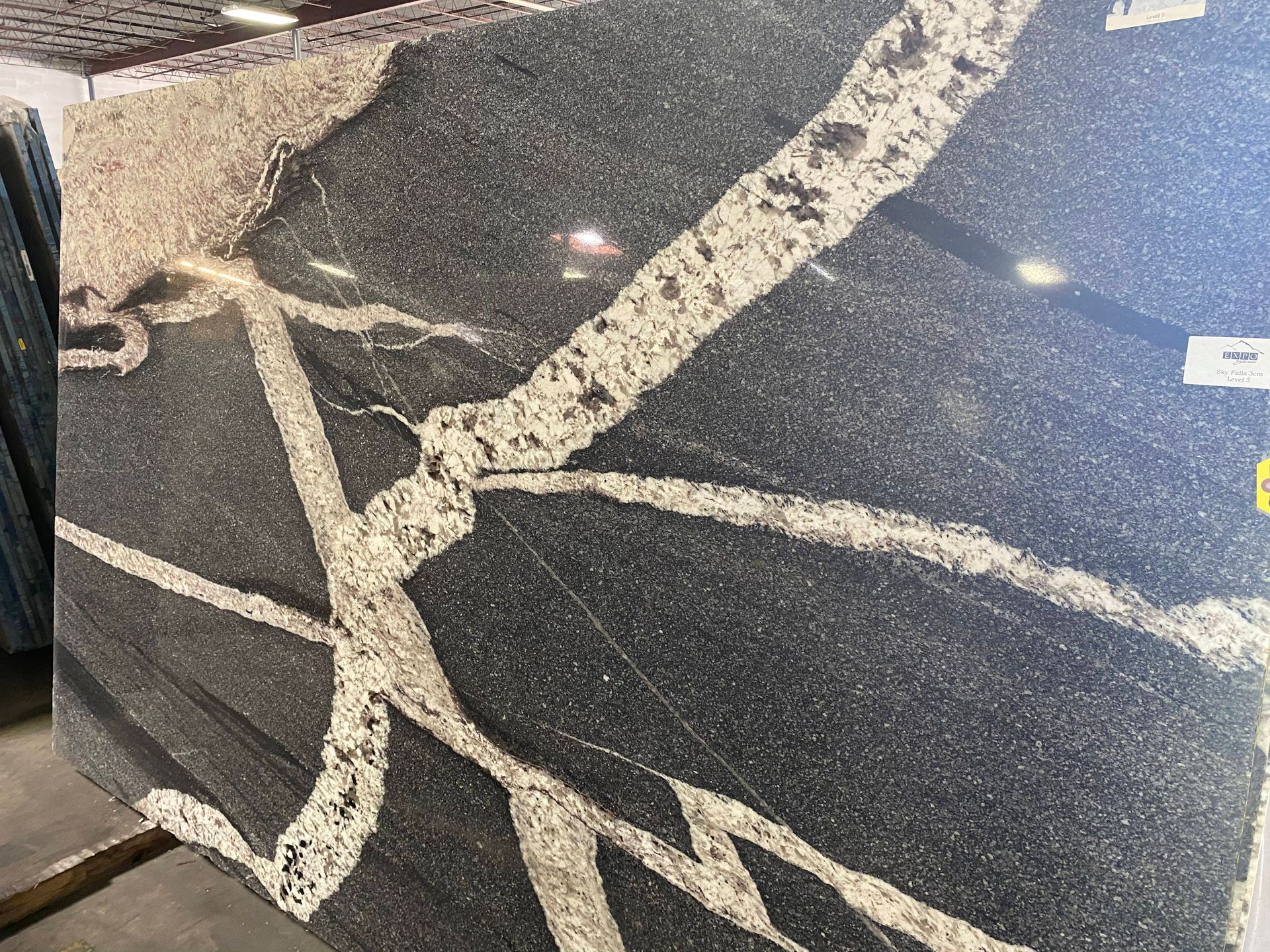 Close-up of a dark speckled stone surface with light beige veining and a polished finish
