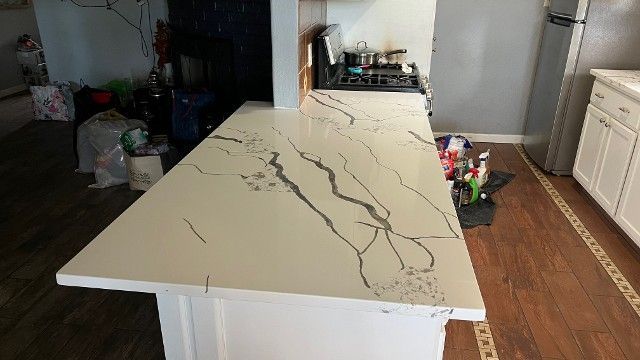 Kitchen island with white countertop and black veining, shown in a home interior.