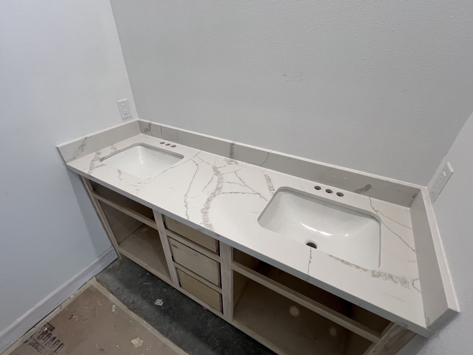 White quartz bathroom vanity with sink and open cabinets in a small unfinished room
