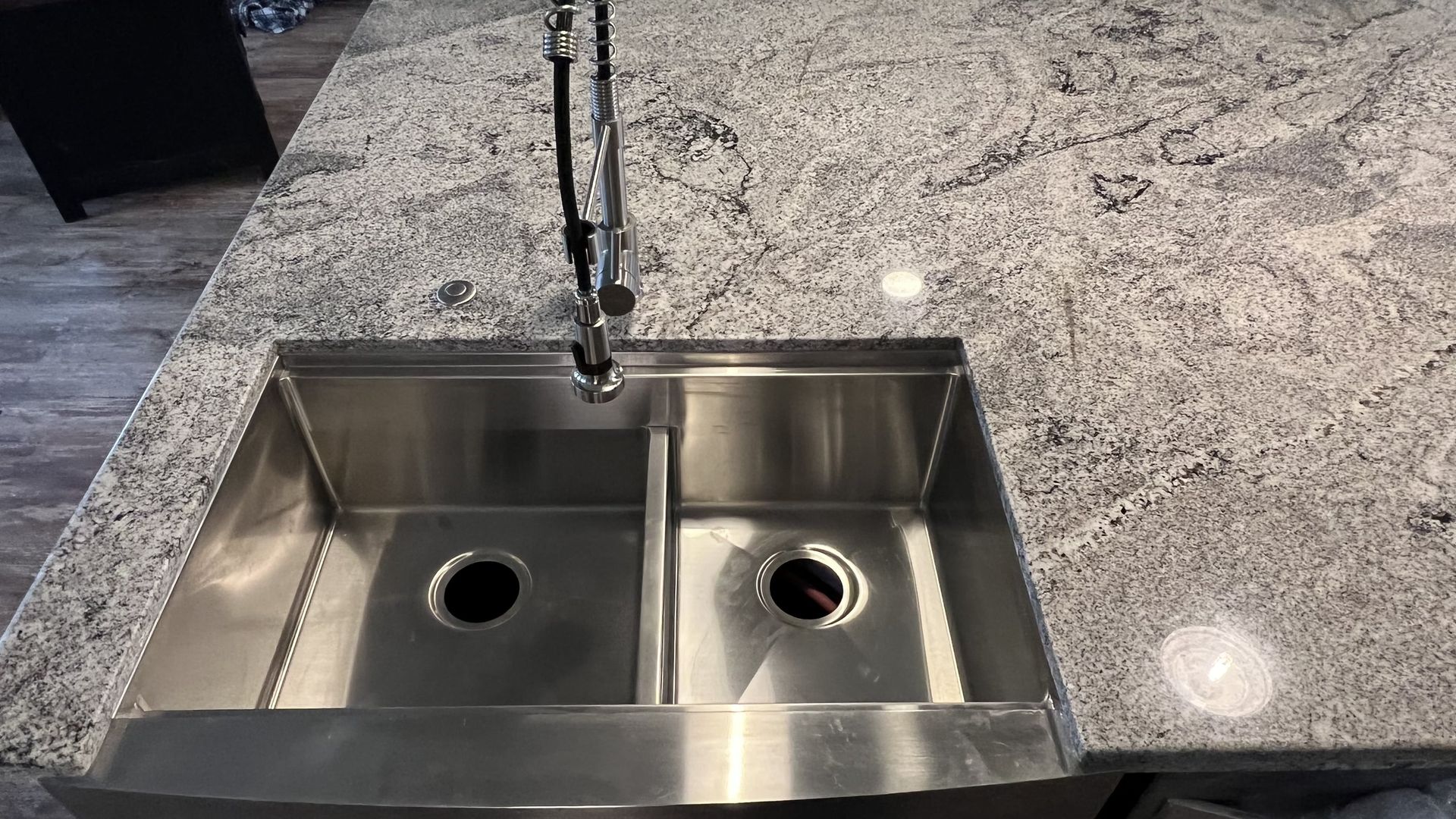 Stainless steel double-basin kitchen sink with faucet on a granite countertop