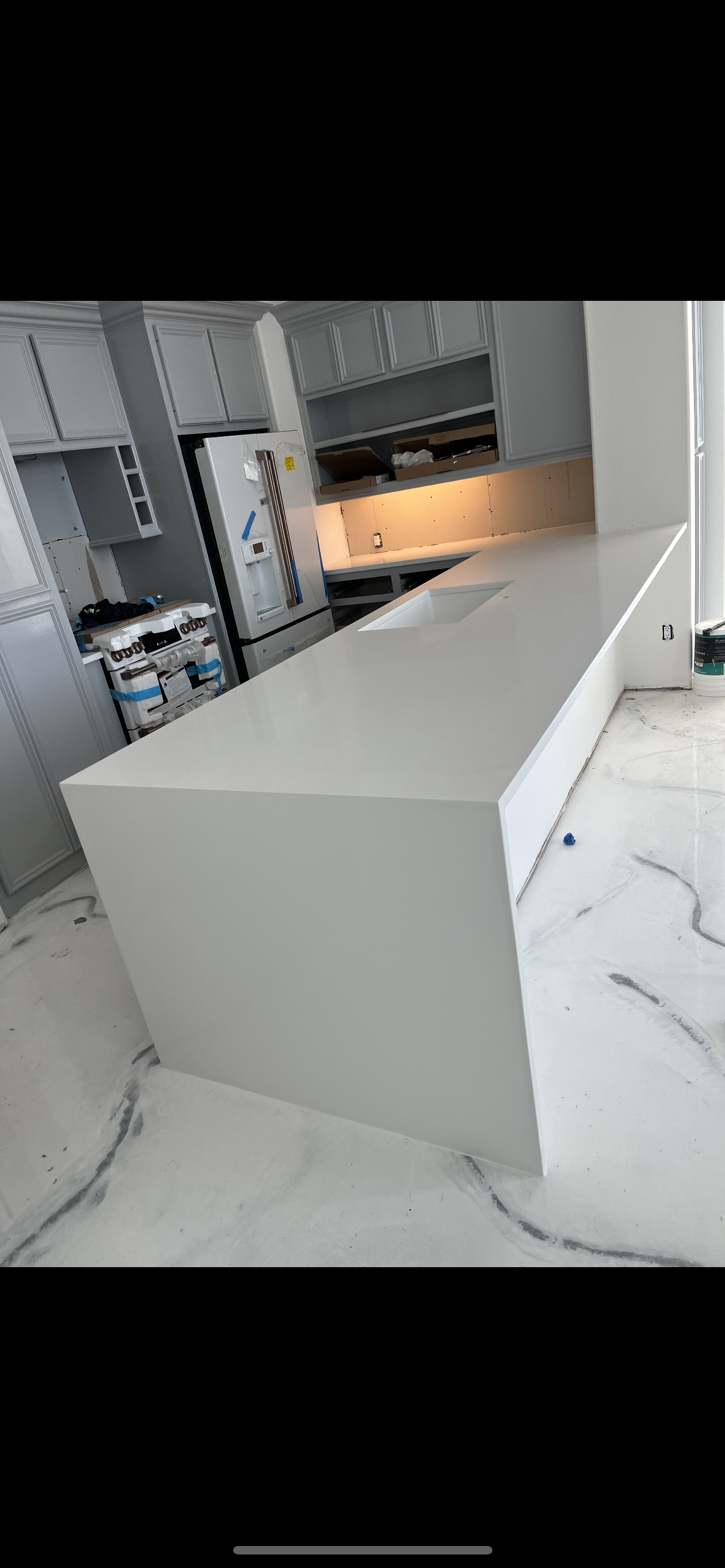 Modern kitchen with a large white island and built-in oven, viewed from the counter end