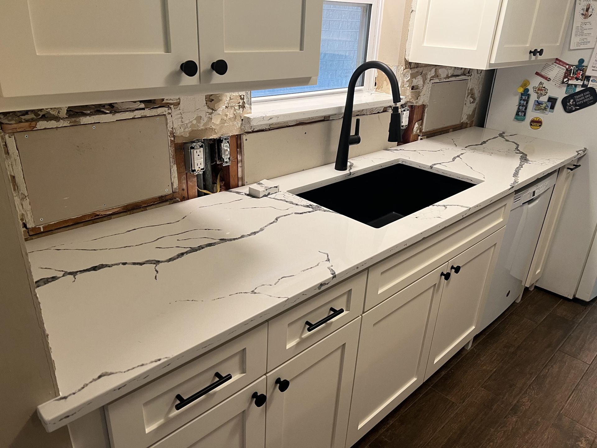 Kitchen countertop with a large cutout for a sink, black faucet, and cabinets below