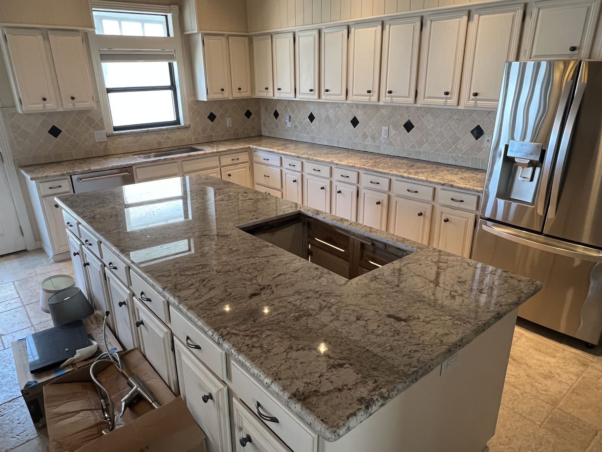 Bright modern kitchen with white cabinets, granite island, and stainless steel appliances