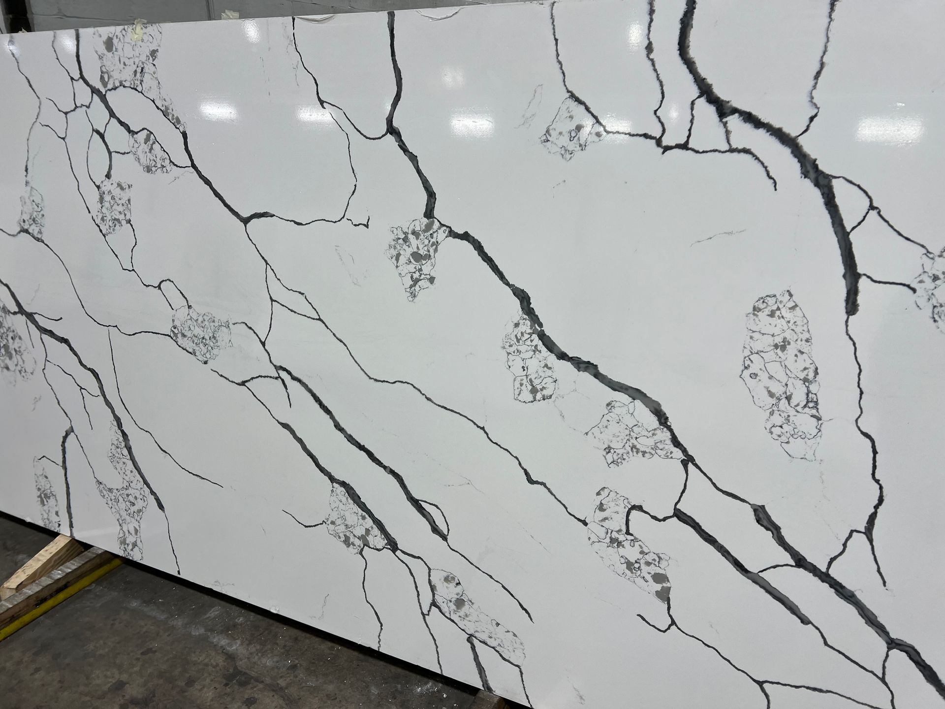 White marble-look countertop slab with gray and black veining and gold accents in a showroom