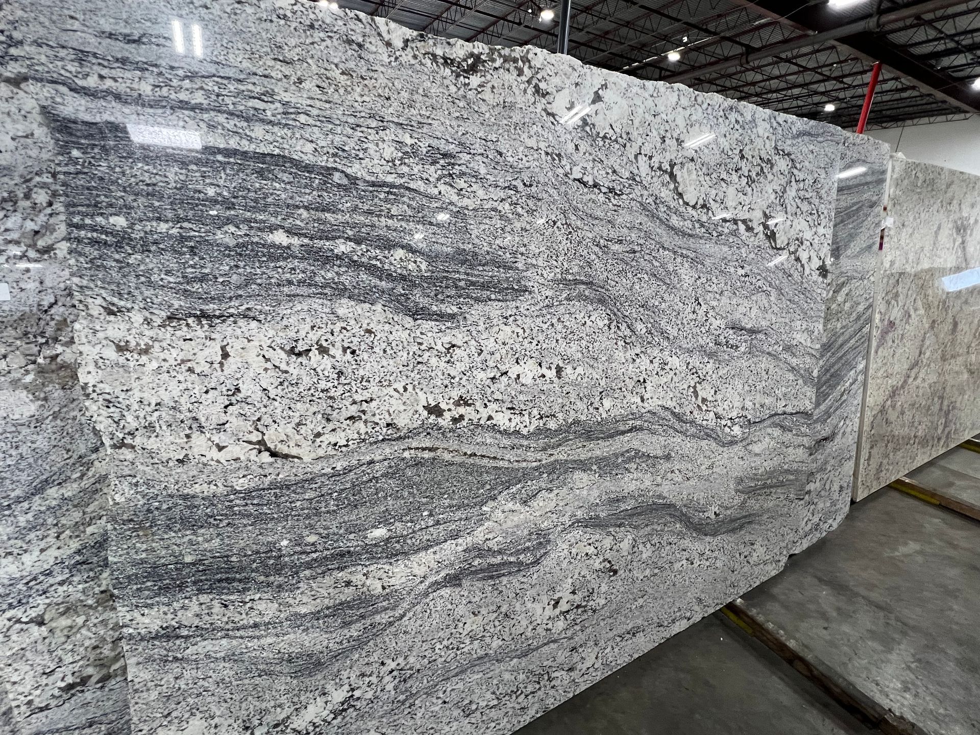 Large polished granite slabs with gray and white swirling patterns in a warehouse showroom