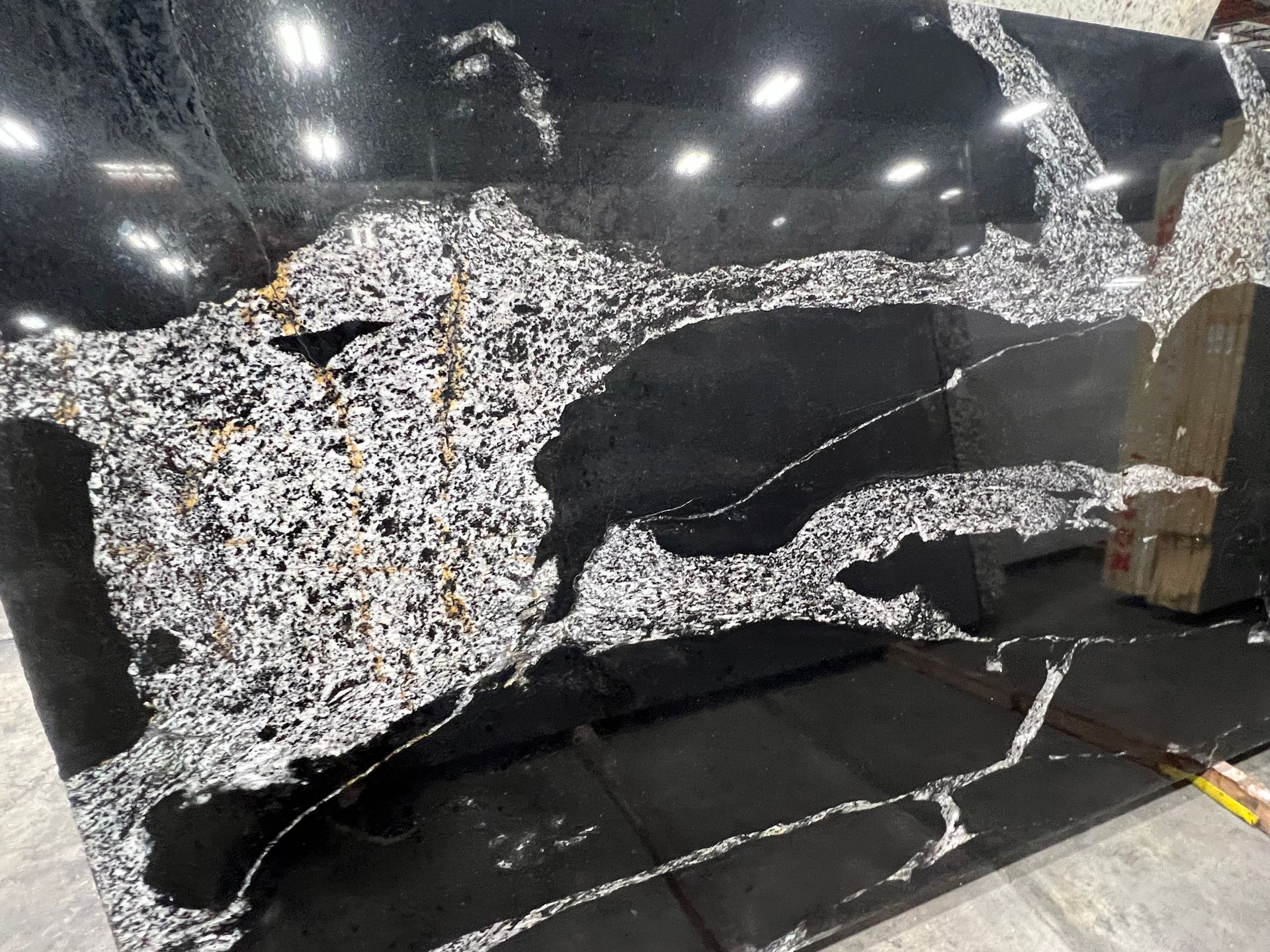 Black car body with large shattered windshield and damaged front panel in a workshop.