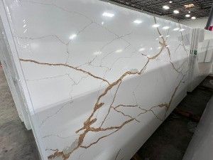 White marble-look slab with gold and gray veining stacked in a warehouse-like showroom.
