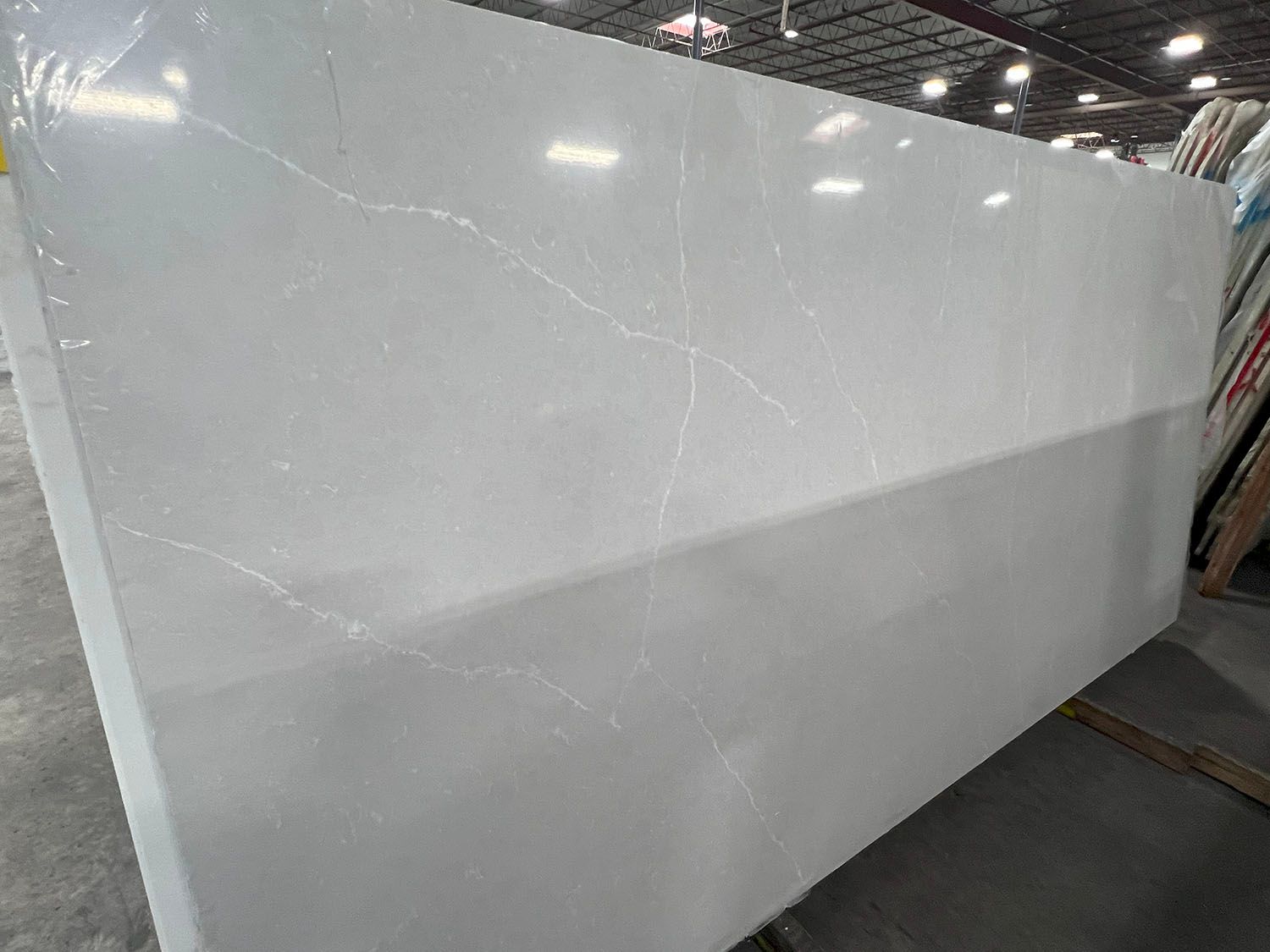 Large glossy white panel leaning in an indoor showroom or warehouse