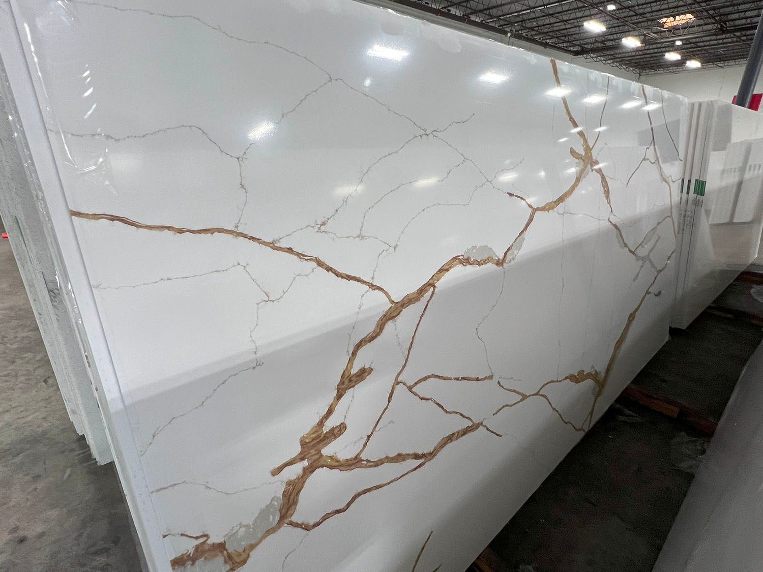 Large white marble slab with gold veining stacked in a warehouse or stone yard.