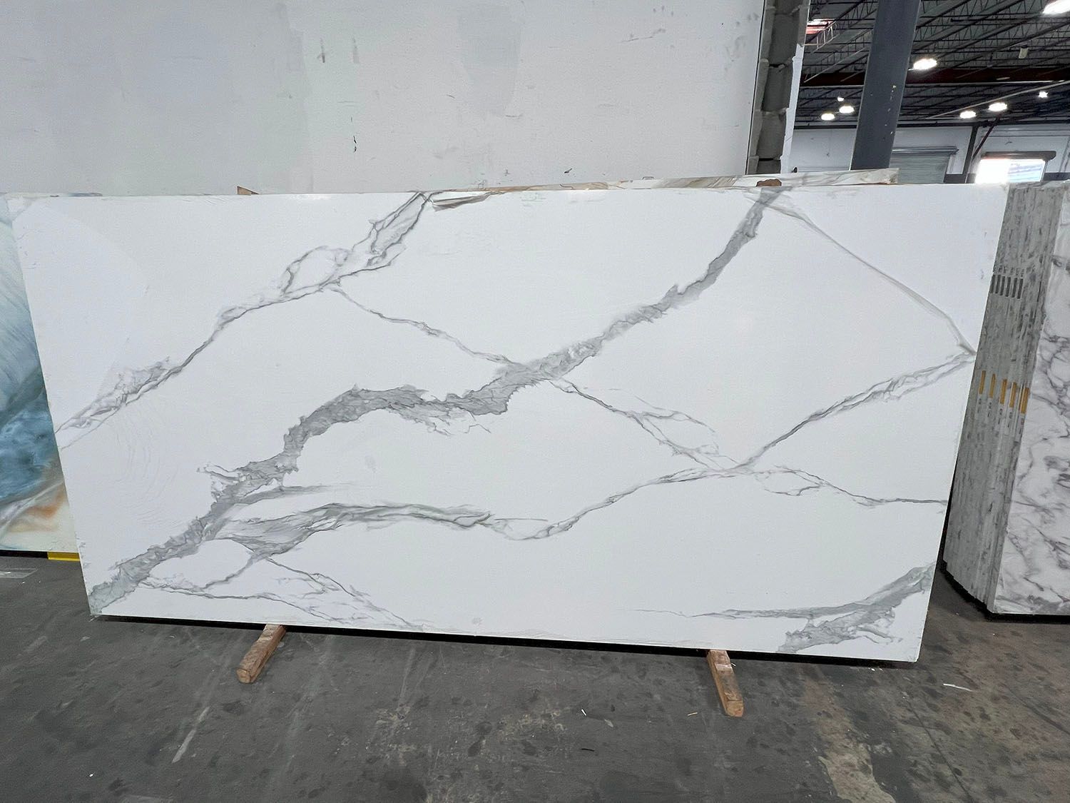 Large white marble slab with gray veining leaning in a warehouse or workshop