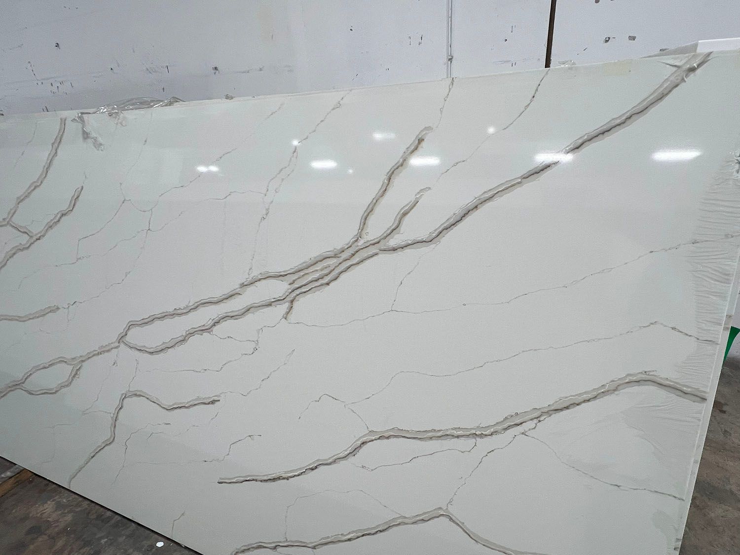 White marble-look tile panel with gray veining and subtle gold accents against a light wall