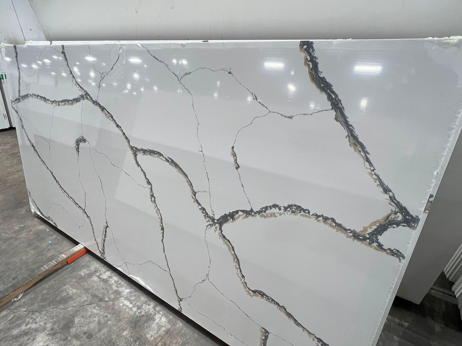 White marble-look slab with gray veining leaning in a workshop or stone showroom