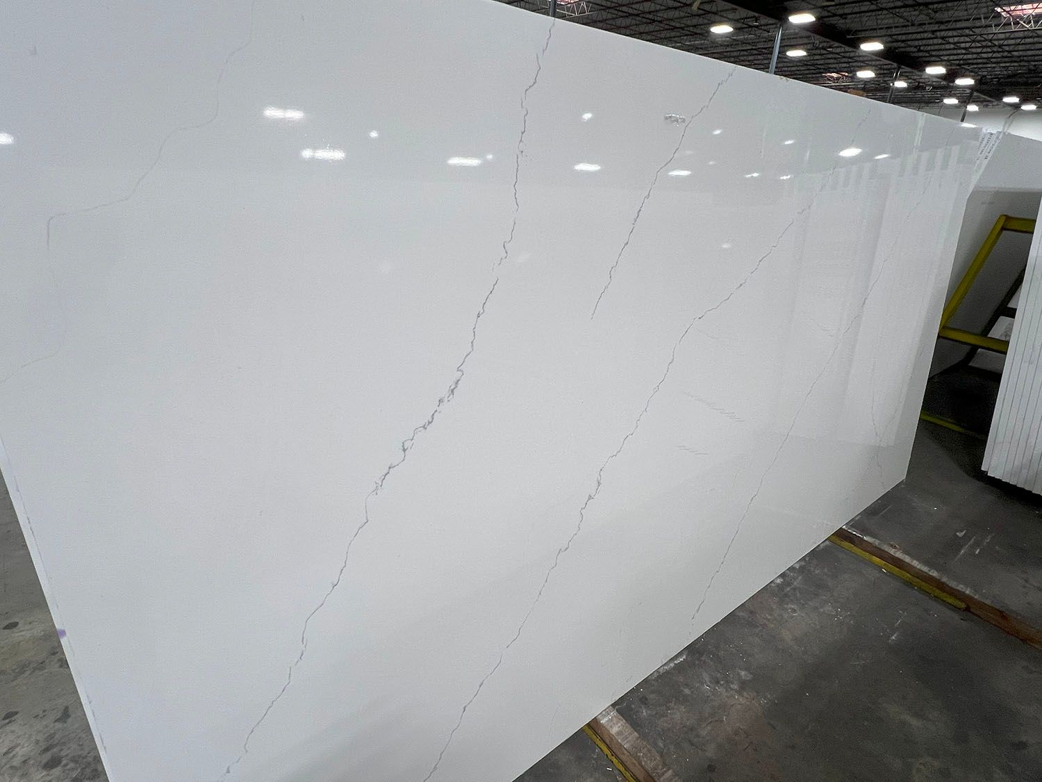 White tiled wall with a long diagonal crack near a gray floor in a parking garage