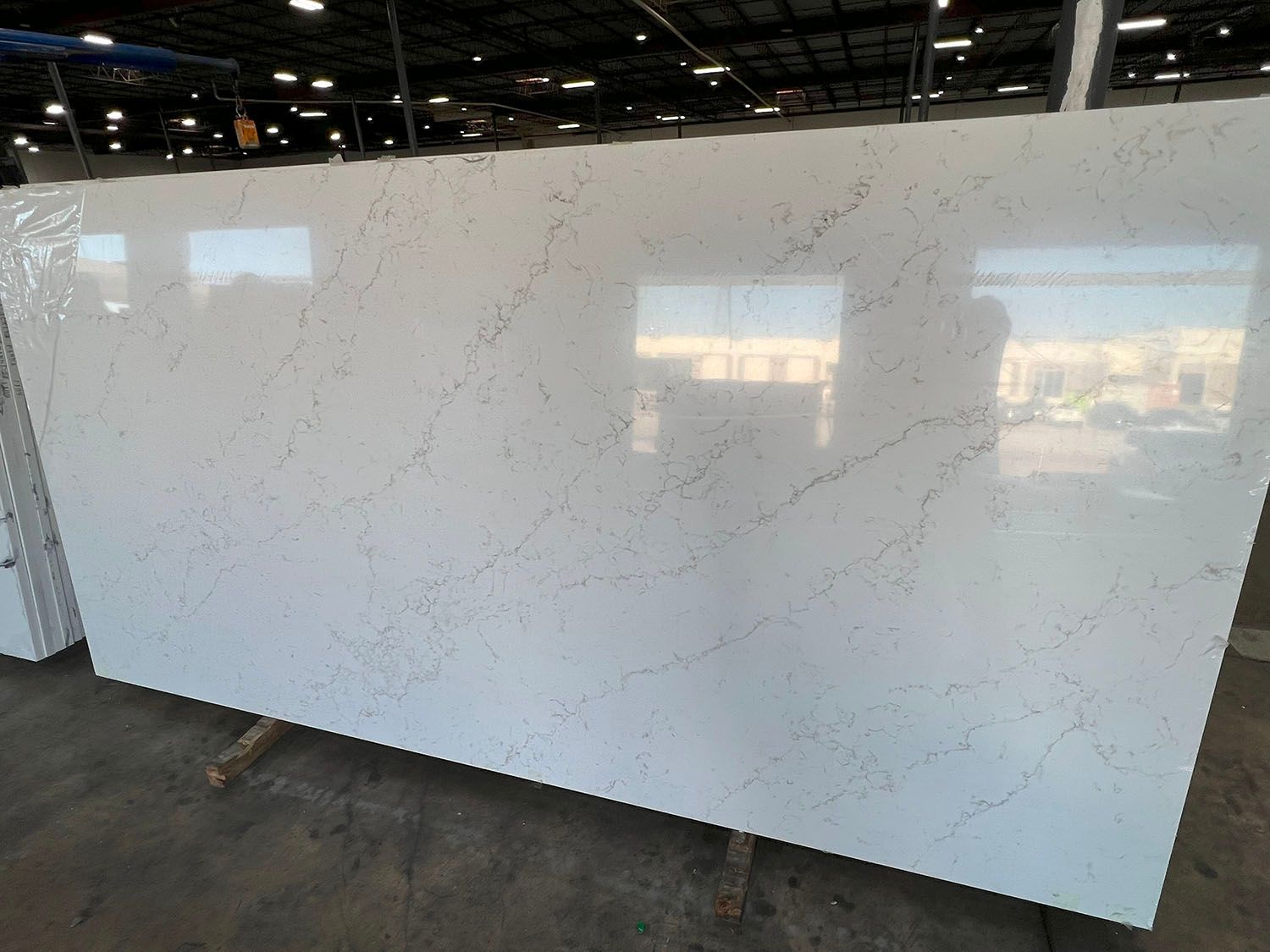 Large white veined quartz slab standing upright in an industrial warehouse showroom