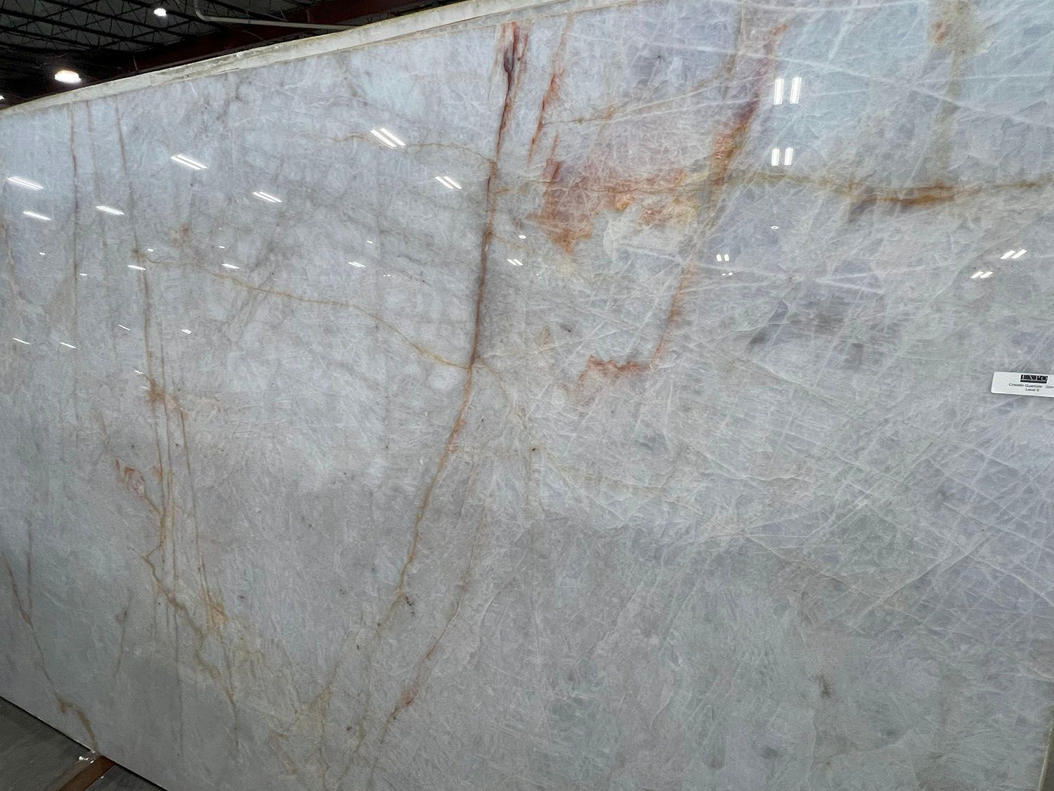 Large gray marble slab with brown veining, viewed in a stone warehouse