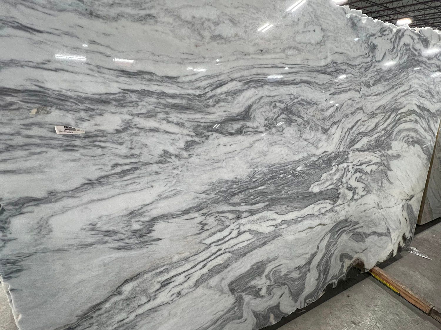 White-and-gray veined marble slab leaning upright, with a small wooden support at the base.