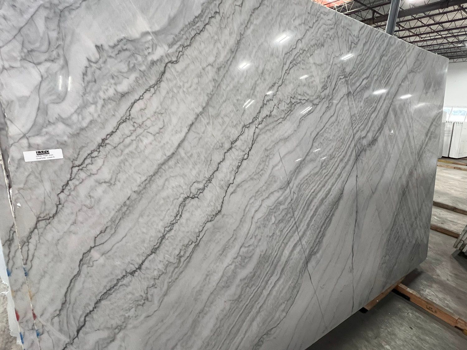 Large gray marble slab with white veining, displayed on a warehouse pallet