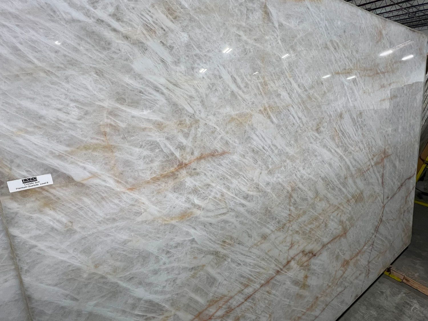 Large white marble slab with gray veining, leaning upright outdoors on a paved surface.