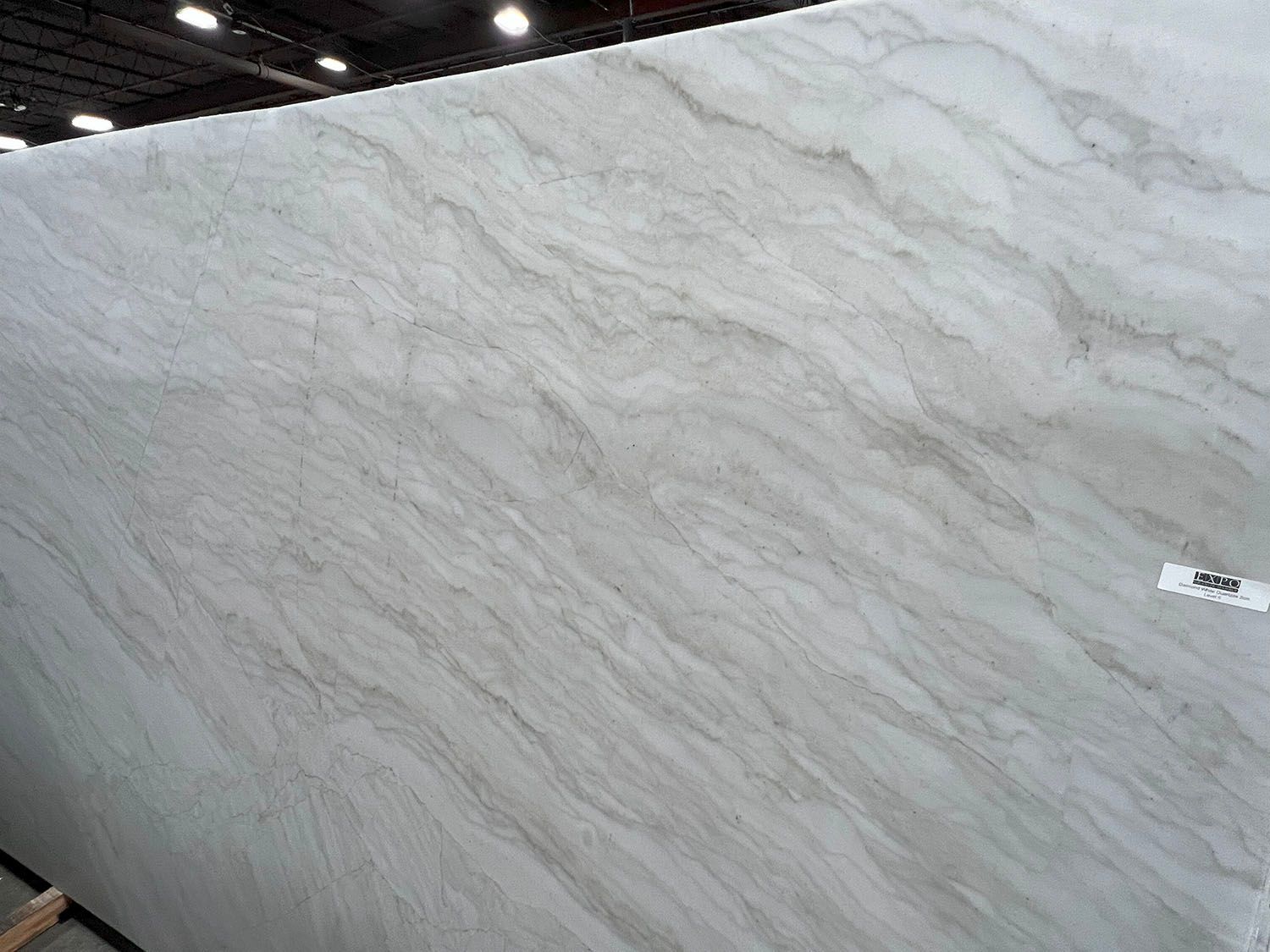 Large textured white marble slab displayed indoors with a small label on the right side.