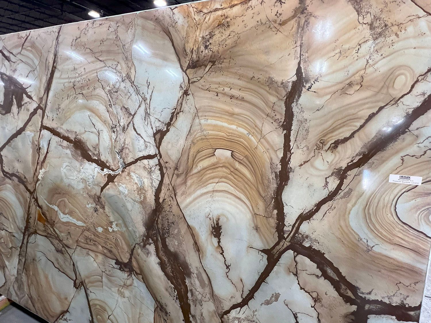 Polished beige marble slab with brown veining and swirling natural stone patterns