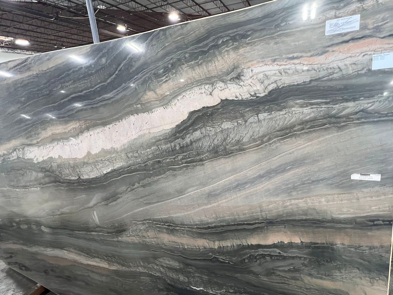 Large polished gray and white veined stone slab displayed in a warehouse