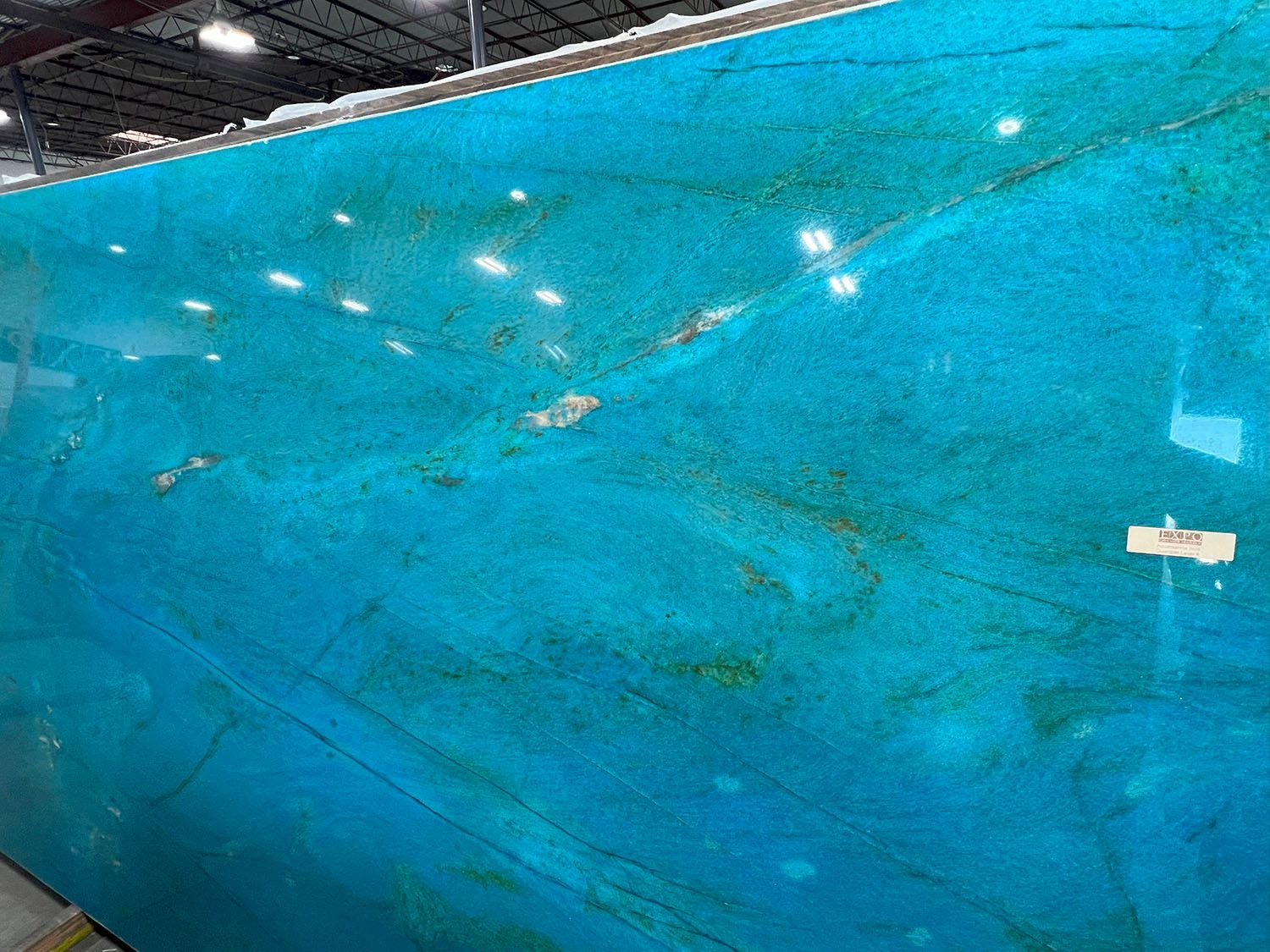Large blue indoor pool with lane lines and overhead lights, viewed at an angle