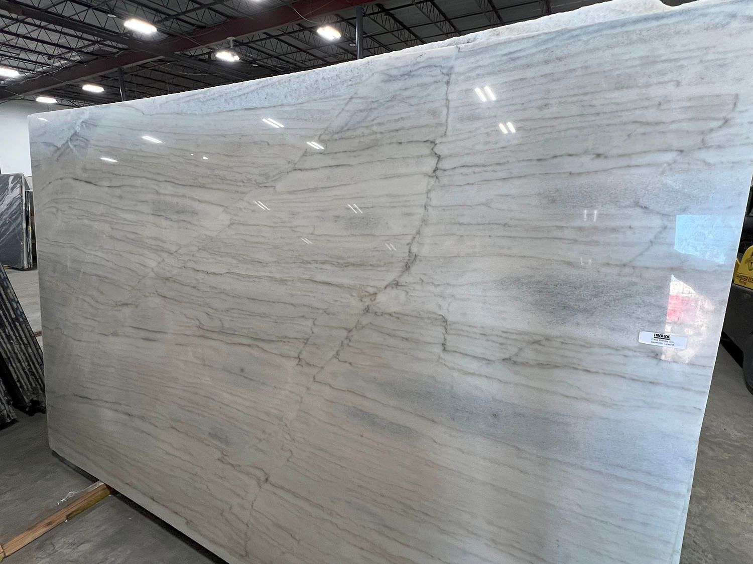 Large white veined marble slab displayed upright in a warehouse or showroom