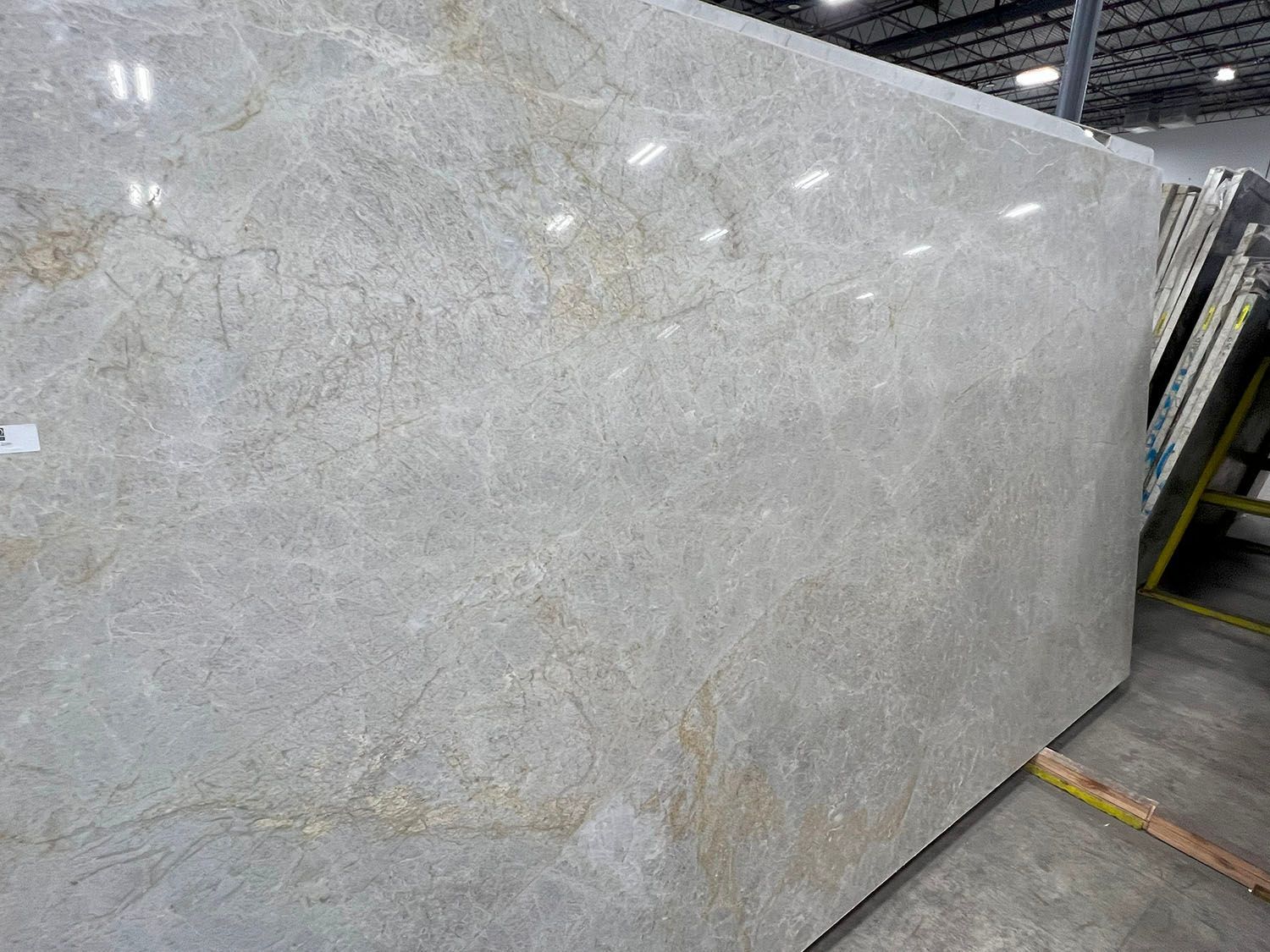 Large gray stone slab leaning upright in a warehouse or stone yard.