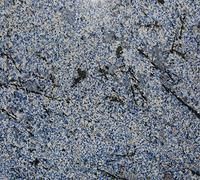 Close-up of a gray speckled surface with dark streaks and scattered debris