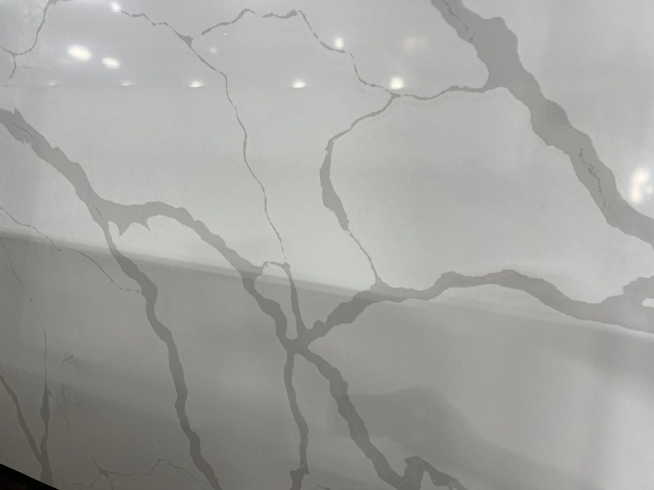 Close-up of glossy white marble with gray veins and reflective light spots