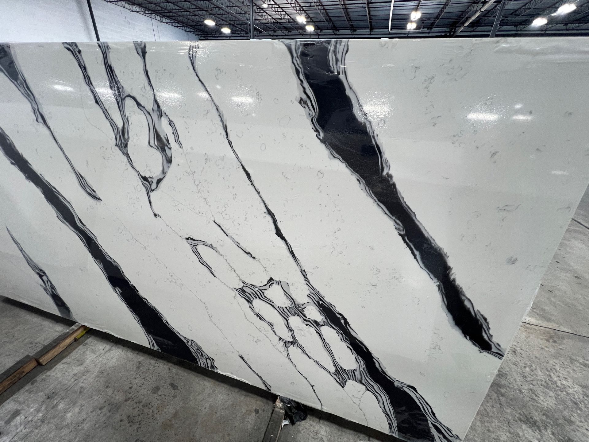 Large white marble slab with bold black veining displayed upright in a warehouse-like showroom.