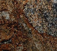 Close-up of rough mottled brown, gray, and black stone surface with speckled texture