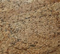 Close-up of rough tan and brown stone surface with speckled texture