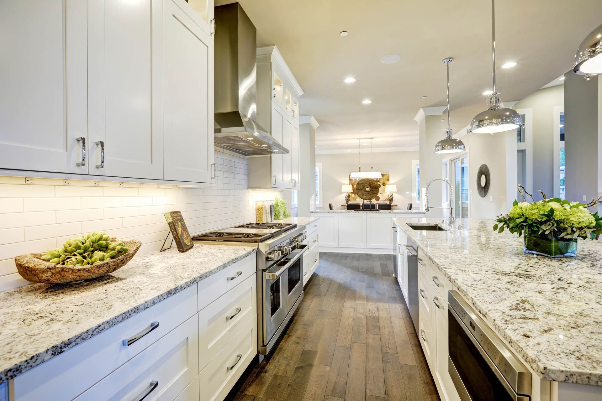 Bright white modern kitchen with marble counters, island seating, and wood floors