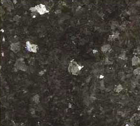 Dark, grainy close-up of a rough black-and-gray textured surface with small white specks