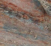 Close-up of layered rock with gray, rust, and blue mineral streaks