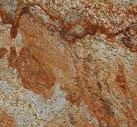 Close-up of rough gray stone with rust-colored veins and patches