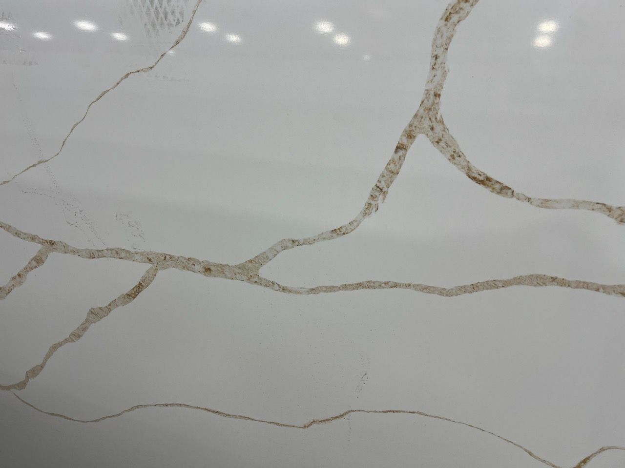 Cracked white marble surface with thin gray veining and a few tan fracture lines