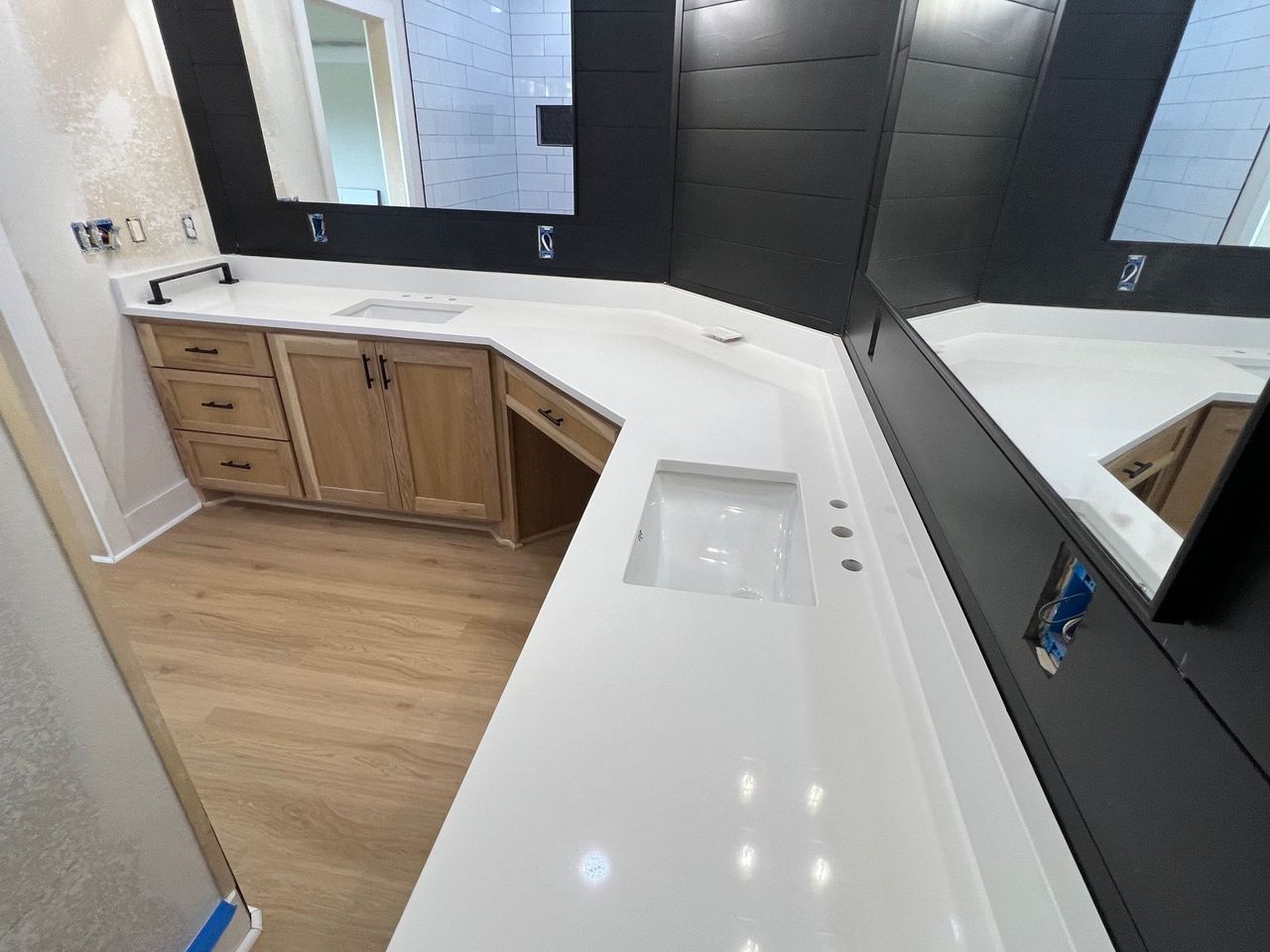 Modern bathroom vanity with double sinks, white countertop, wood cabinets, and large wall mirrors