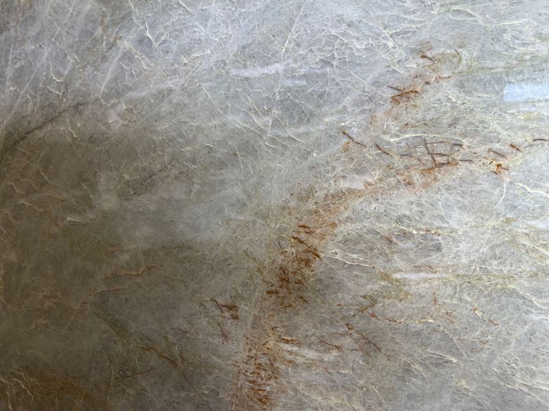 Close-up of a gray, textured stone surface with brown veining and scratches