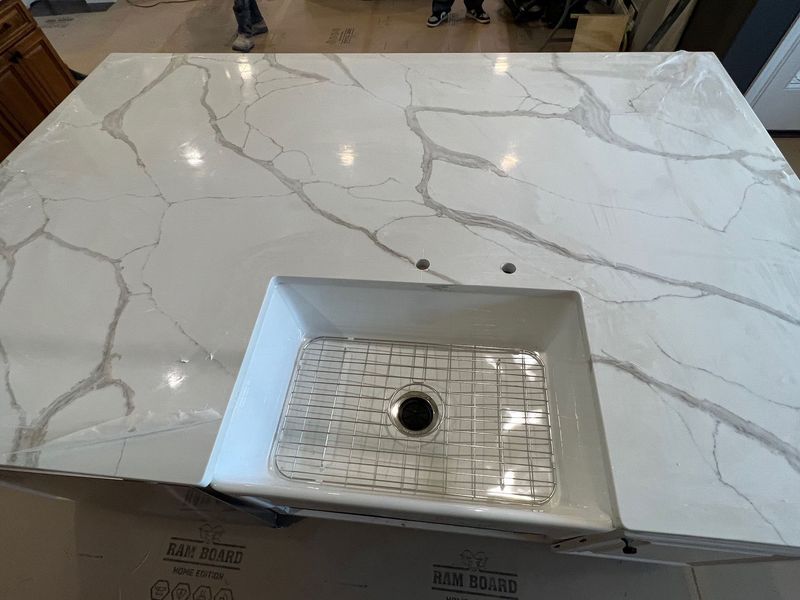 White marble kitchen island with an undermount sink centered in the foreground.