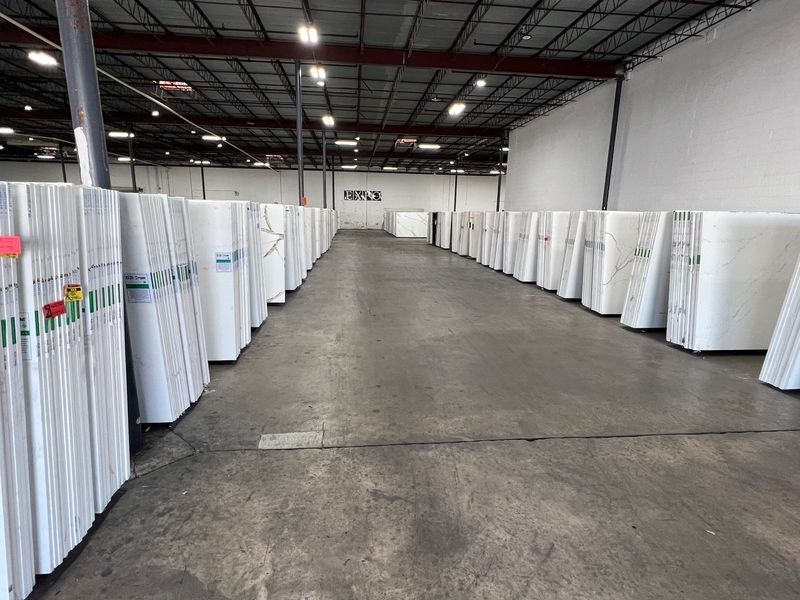 Warehouse aisle lined with stacked white pallets and wrapped materials on both sides