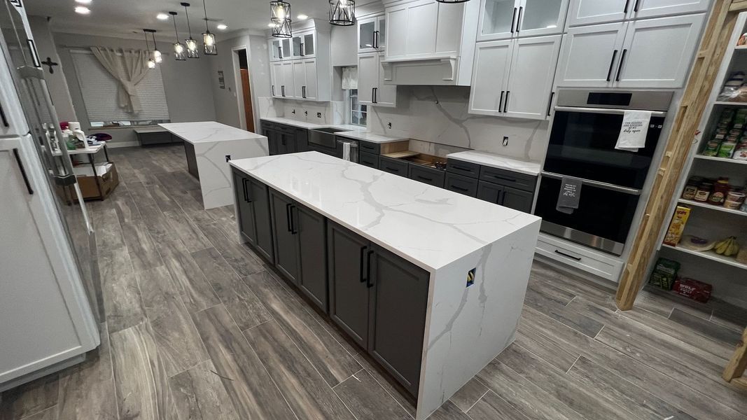 Bright modern kitchen with gray island cabinets, white countertops, and stainless appliances